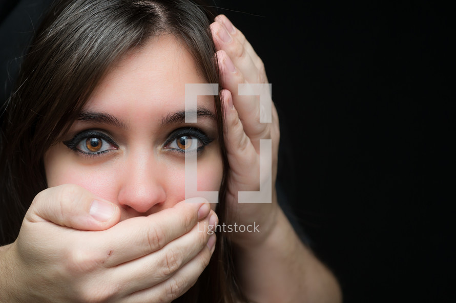 Hear no evil; speak no evil.   A woman with her mouth and ear covered by a man's hands.