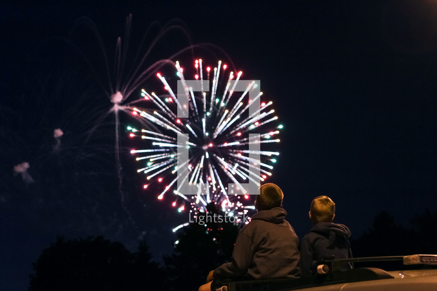 boys watching fireworks in the night sky