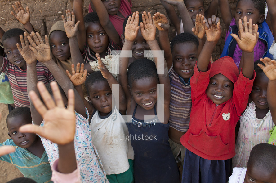 Children in Malawi, Africa with hands raised. 