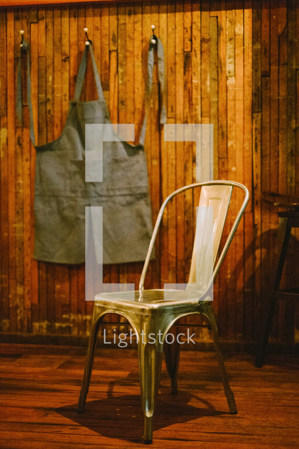 A apron hanging on a hook and a chair. 