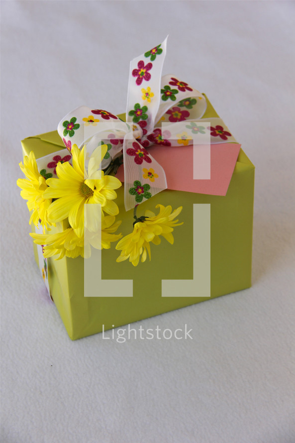 Small gift with colorful ribbon, yellow flowers and blank card