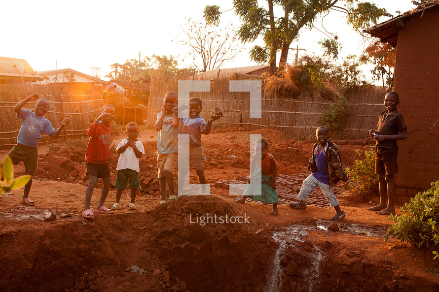 Children playing outdoors in red mud in Malawi, Africa. 