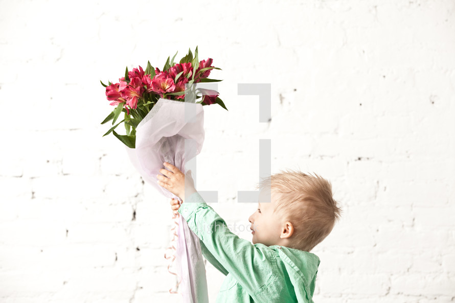 boy holding up a bouquet of flowers