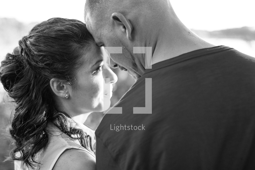 A man and woman standing close together in the sunlight.