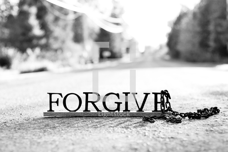 Letters spelling "forgive" on the ground with a chain.
