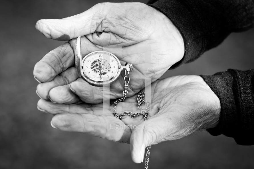 Elderly hands holding a pocket watch.