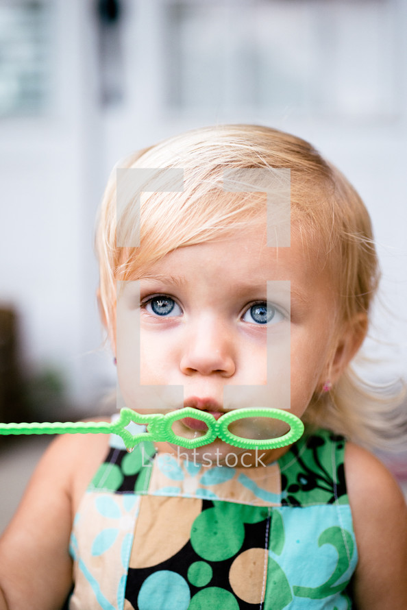 a toddler girl blowing bubbles 
