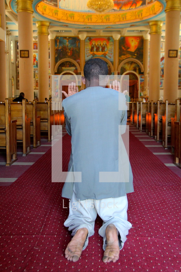 an arab man kneeling in prayer 