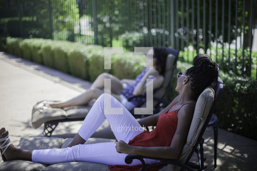 women sitting on lounge chairs relaxing outdoors 
