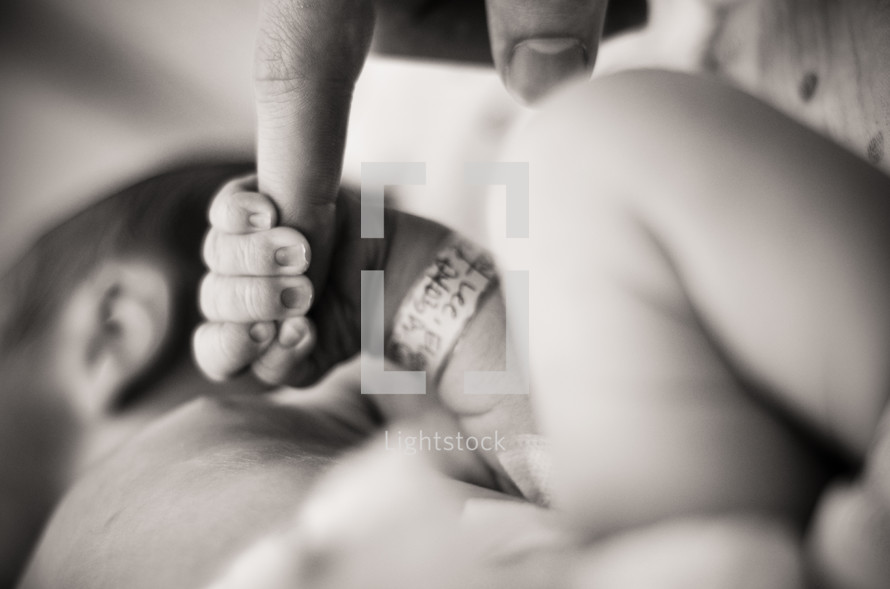 Infant holding father's finger