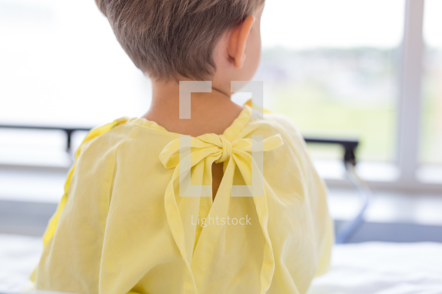 a boy child in a hospital gown walking through a hospital 
