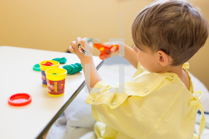 a boy child in a hospital gown playing games in a hospital bed 