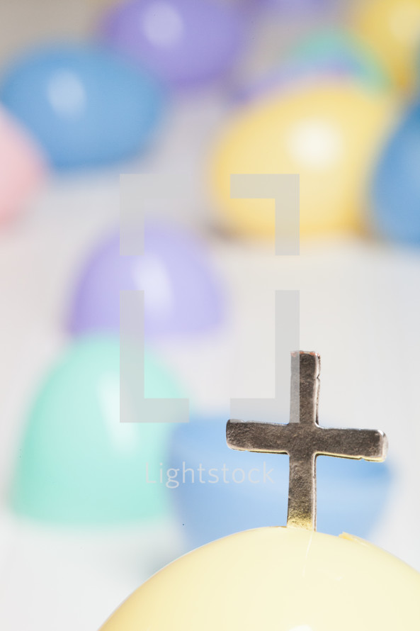 Silver cross protrouding from a plastic Easter egg.