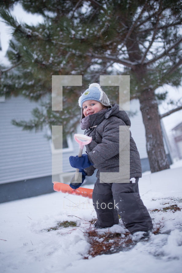 a boy child shoveling snow