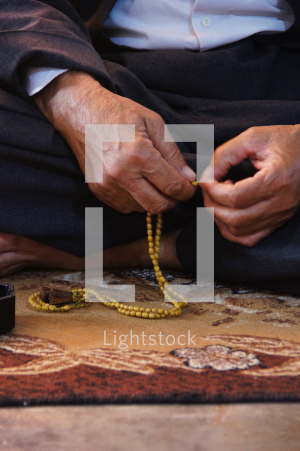 Man praying using prayer beads.