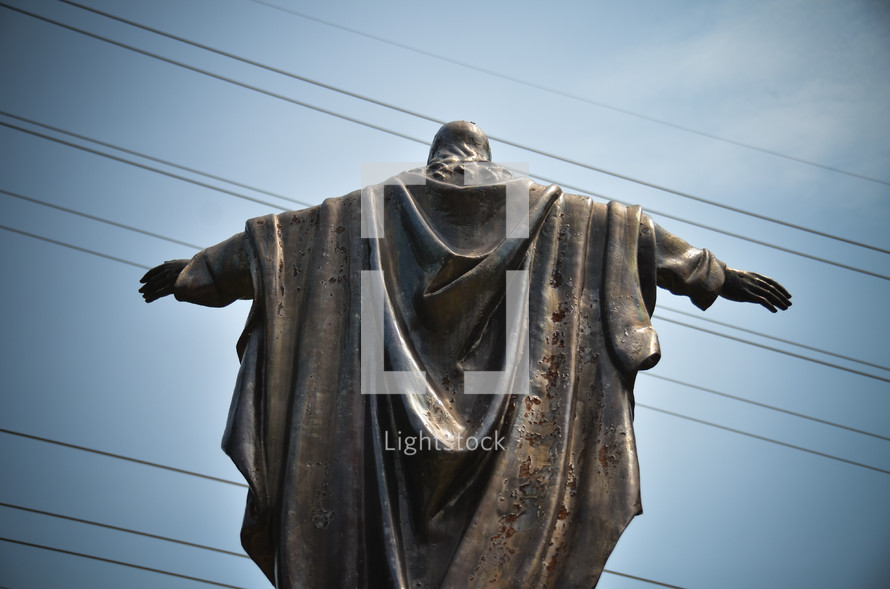 statue of Jesus with his arms outstretched with power lines in the background