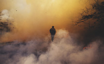 smoke surrounding a fireman as he outs out a forest fire