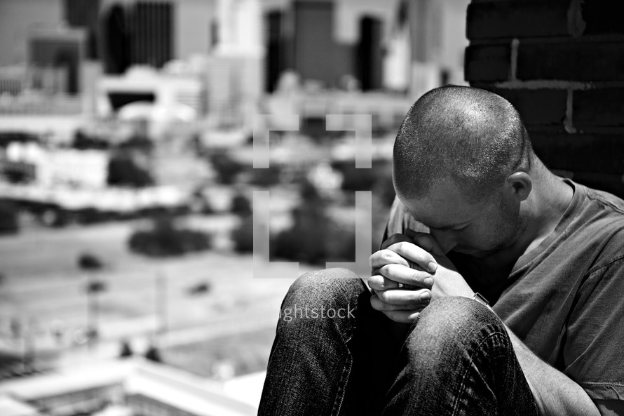 A young man prays on a rooftop.