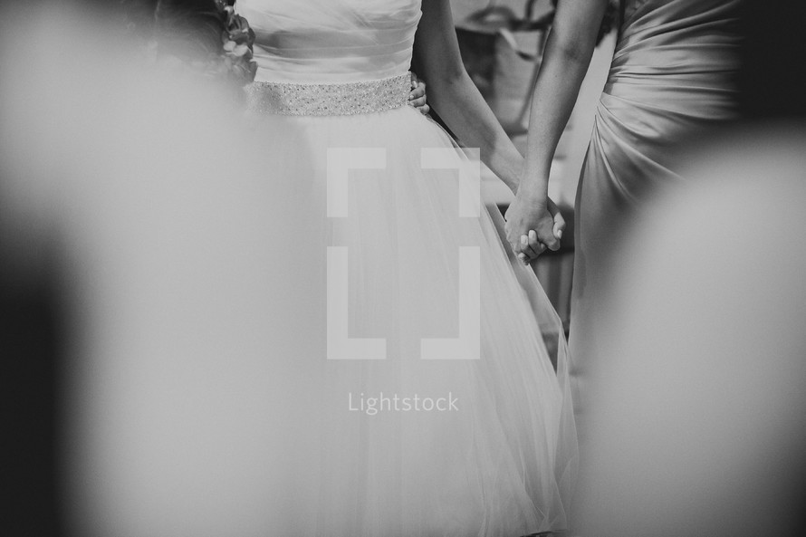 A bride and bridesmaid holding hands at a wedding