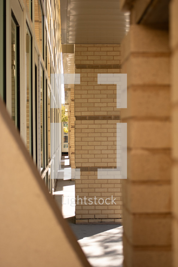 Architectural shot of a building with columns and windows, beige bricks