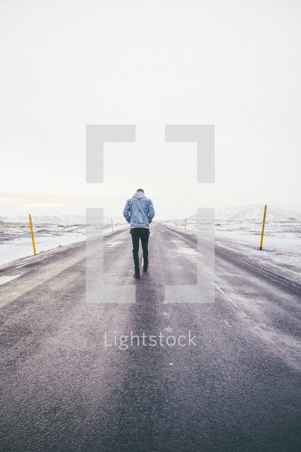 a man standing in the middle of a road alone 
