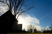 silhouette of a couple kissing by a barn 