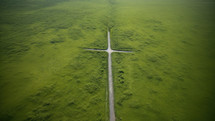 Aerial view of a cross-shaped road in the middle of a green field