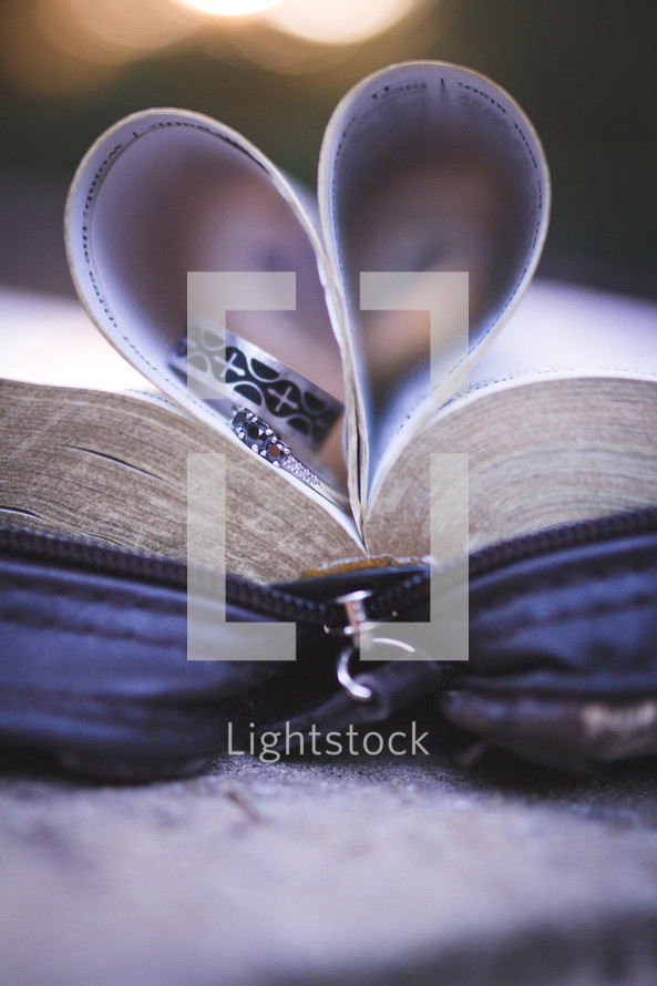 rings on the pages of a Bible and heart shaped folded pages 