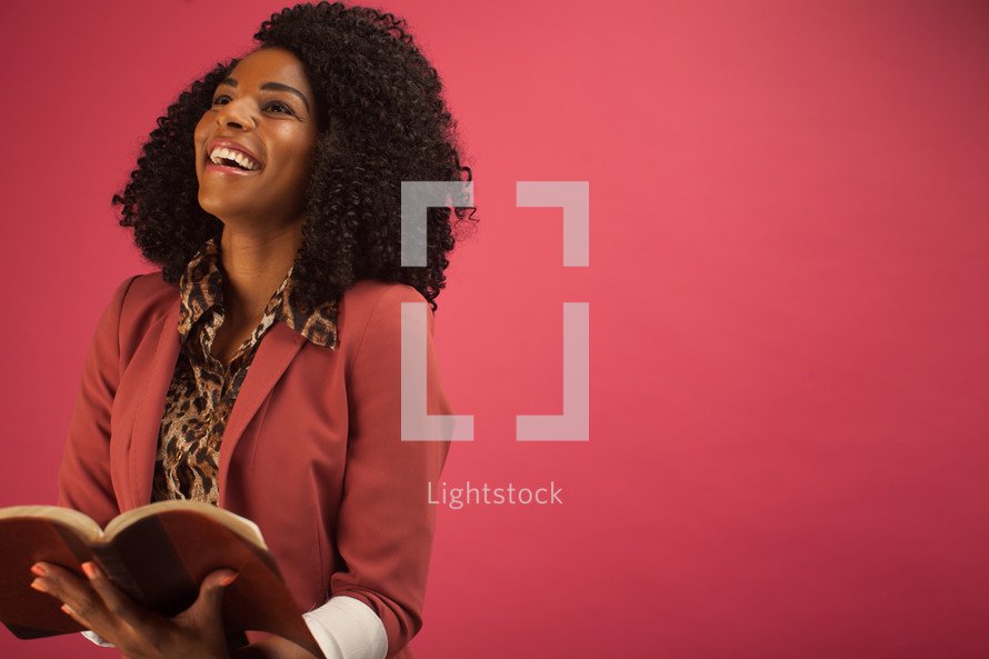 African American woman reading a Bible - pink background 