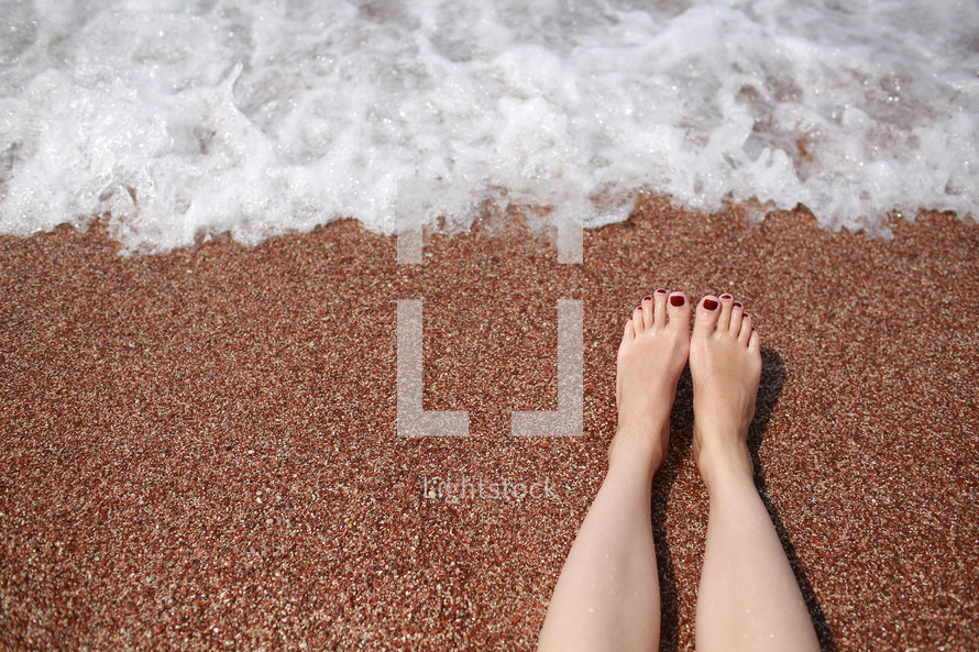 Travel concept - Woman's legs on beautiful tropical beach with pebble sand. Feet on sand and wave in summer time. girl barefoot in ocean water on vacation travel. Feel happy and relax. copy space