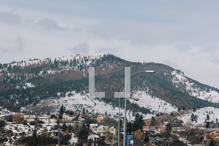 snow on a mountain and a town below 