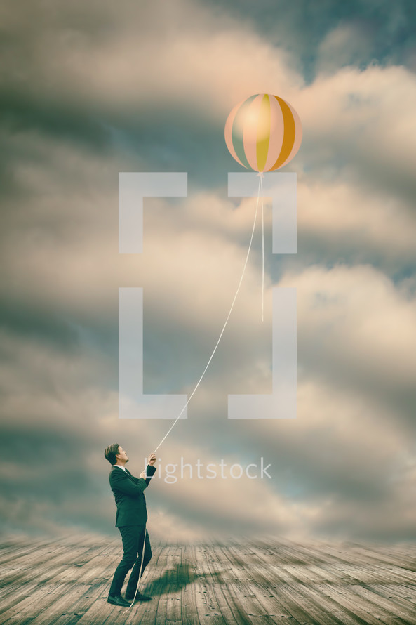 a man hanging onto a balloon 