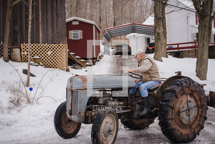 an elderly man on a tractor in winter 