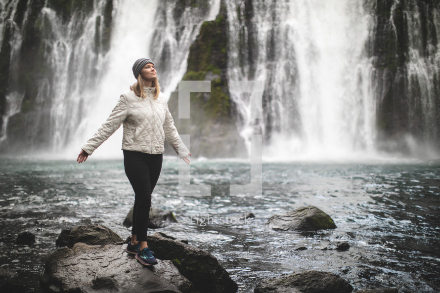 woman standing outdoors with a waterfall in the background 
