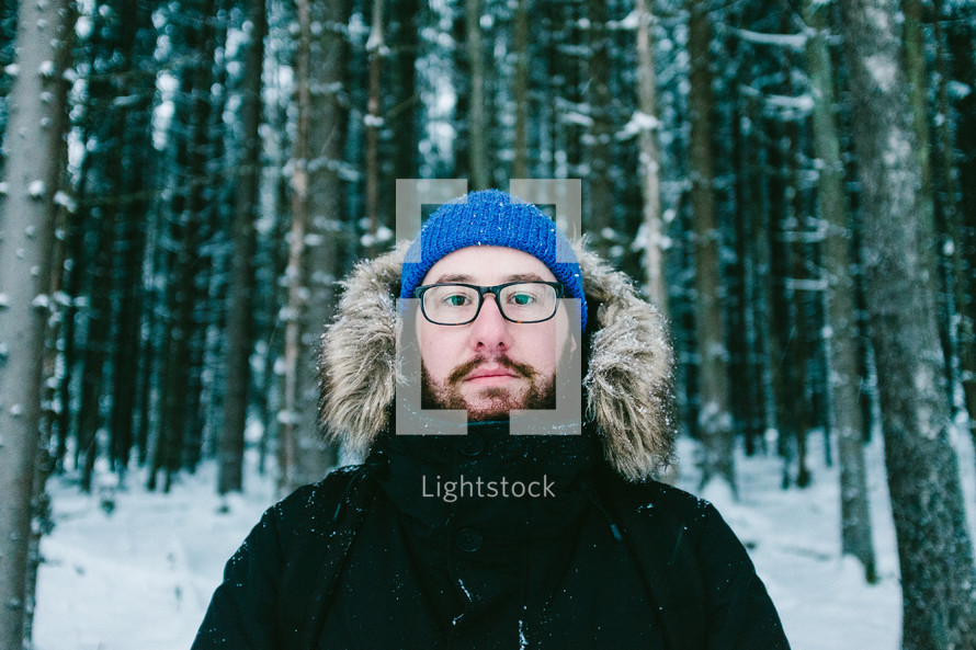 man in a coat standing in a winter forest 