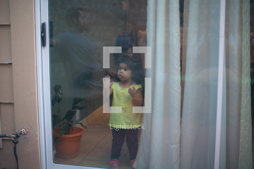 a toddler girl looking out a window 