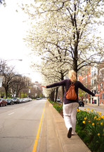 A woman walking along a street, balancing on the curb.