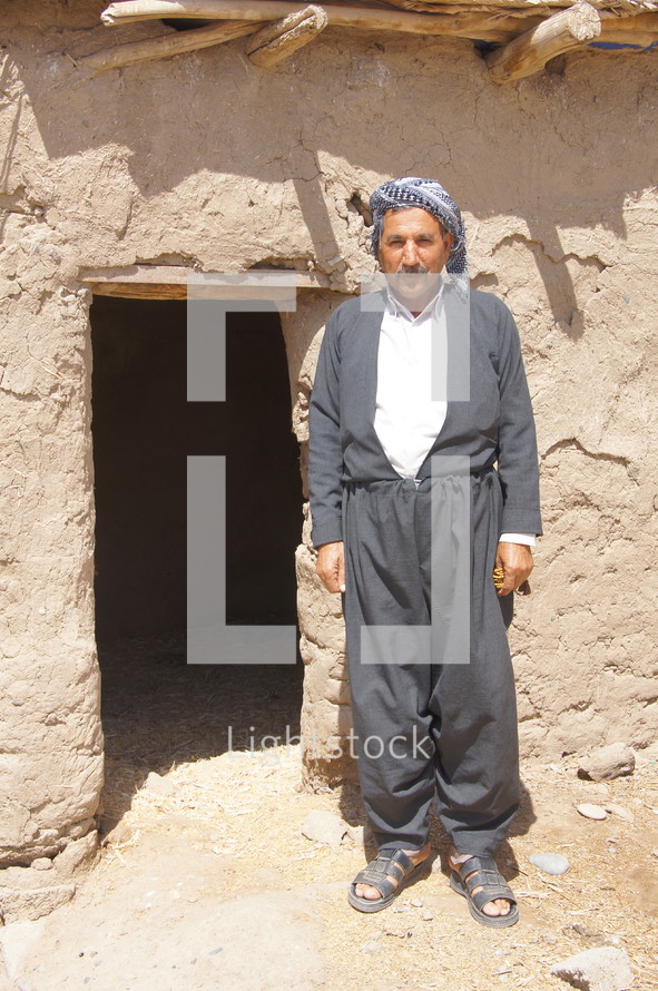 Kurdish man standing at an entrance to a desert home 
