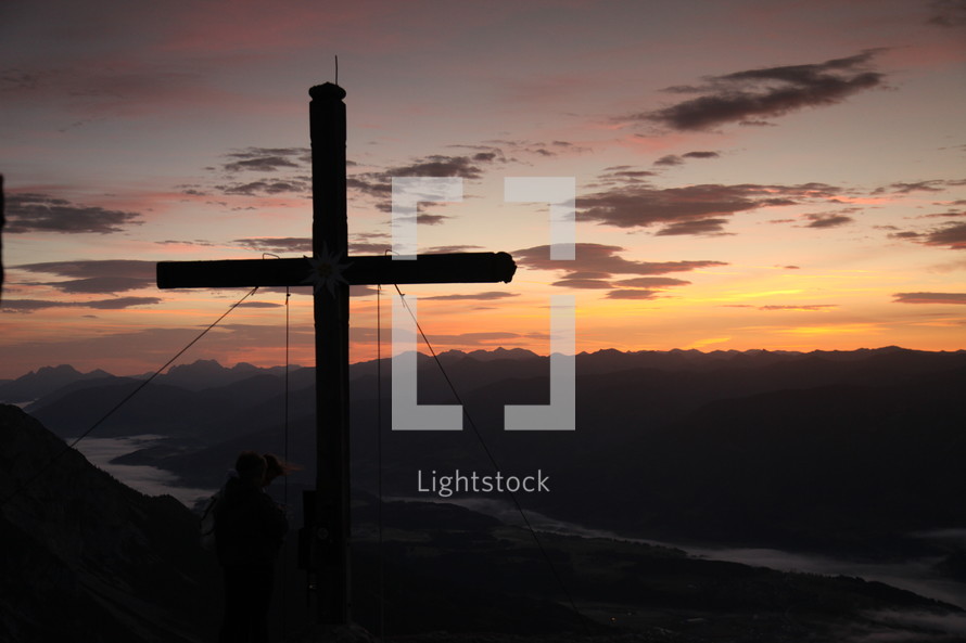 cross at sunset on a mountainside 