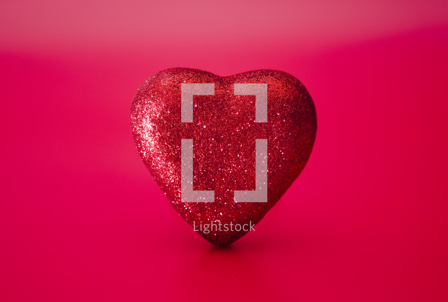 red glittery heart on a pink and red background 