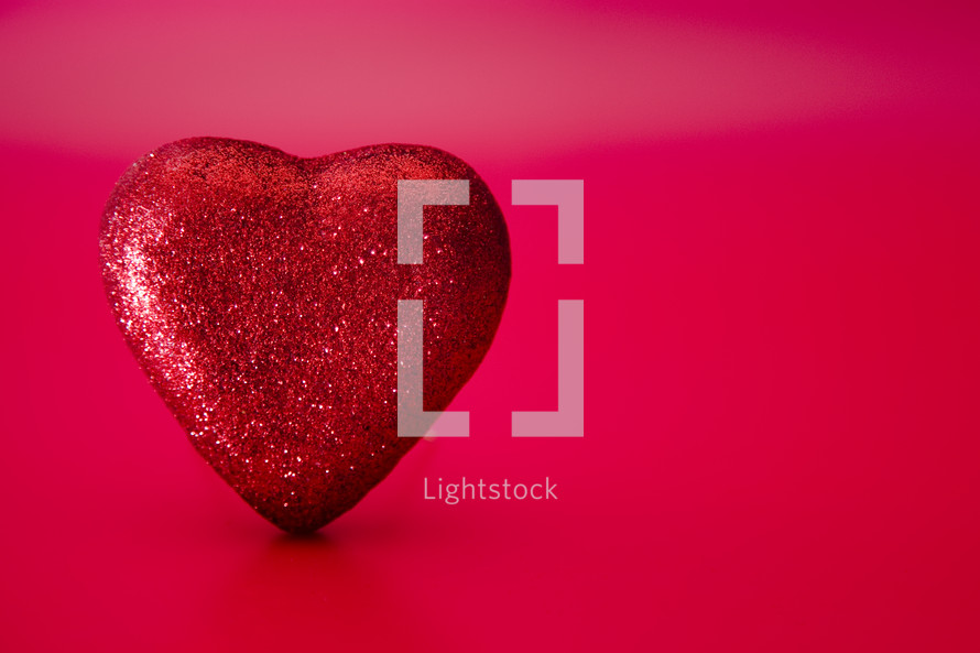 red glittery heart on a pink and red background 