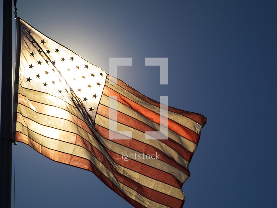 Sun shining through an American flag.
