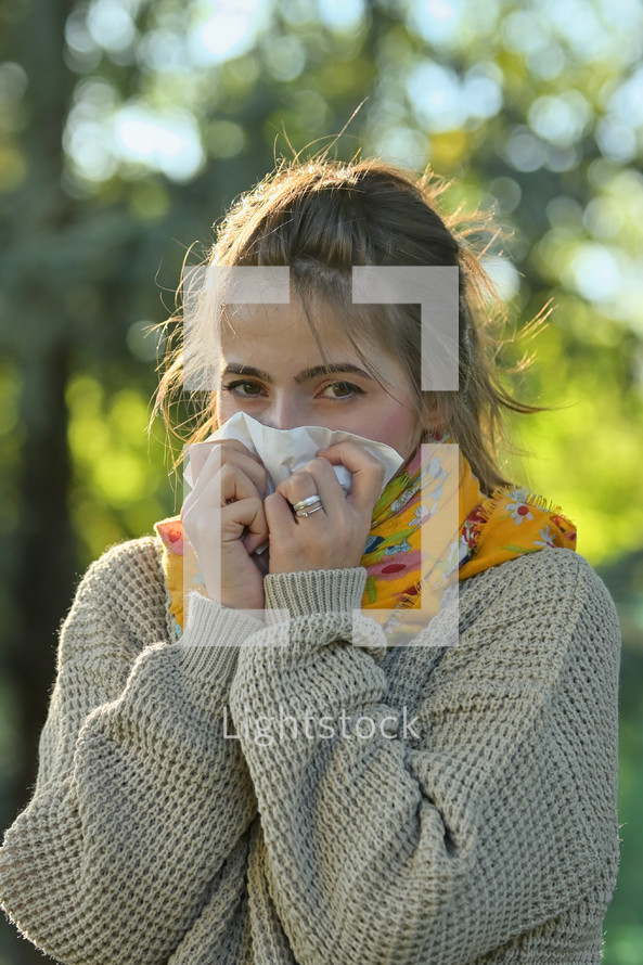 Girl in fall autumn sneezing in tissue