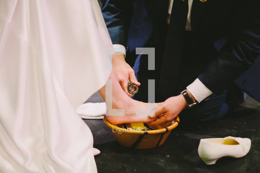 A groom washing his brides feet. 