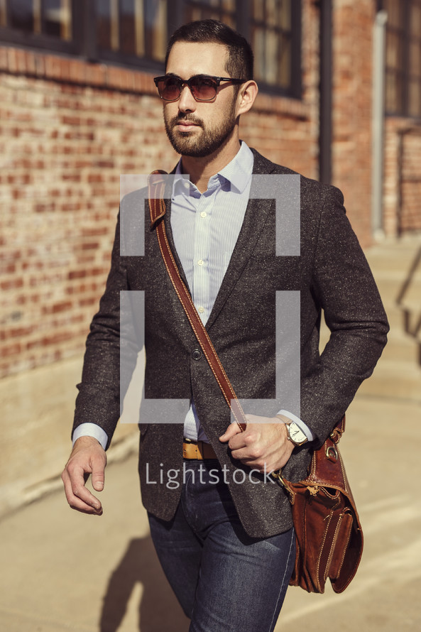 a man in a blazer carrying a satchel walking to work 