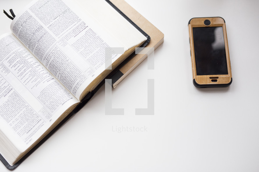 Bible, journal, and cellphone on a white table 