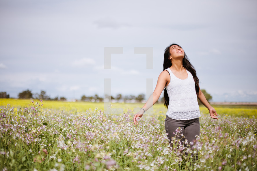 Praising woman standing in a field of flowers.