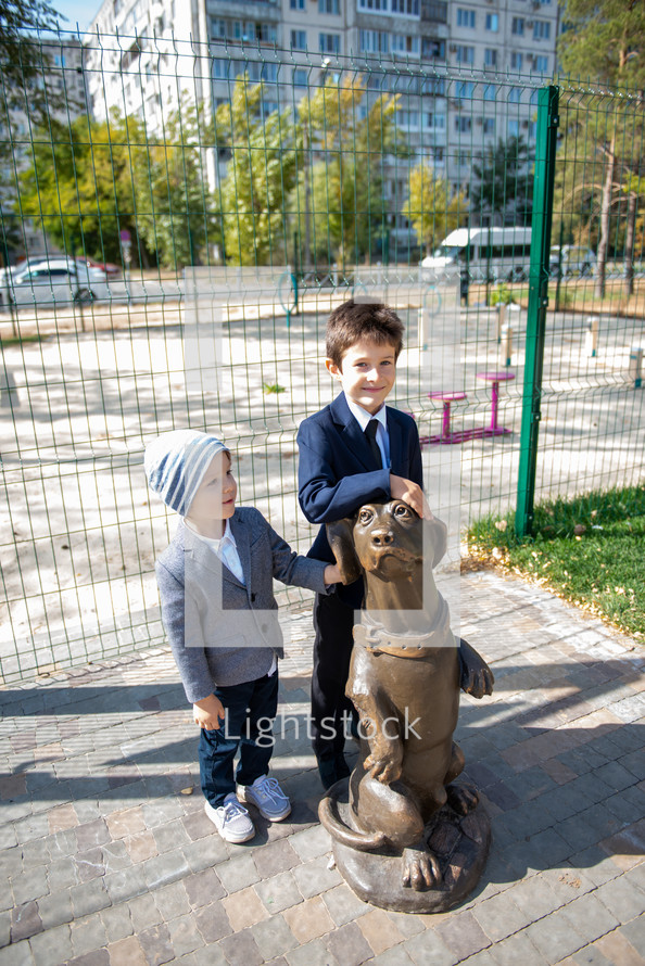Portrait of brothers hugging a dog statue 