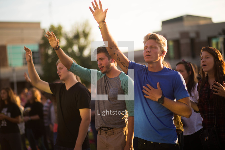group of people with their hands raised praising God 