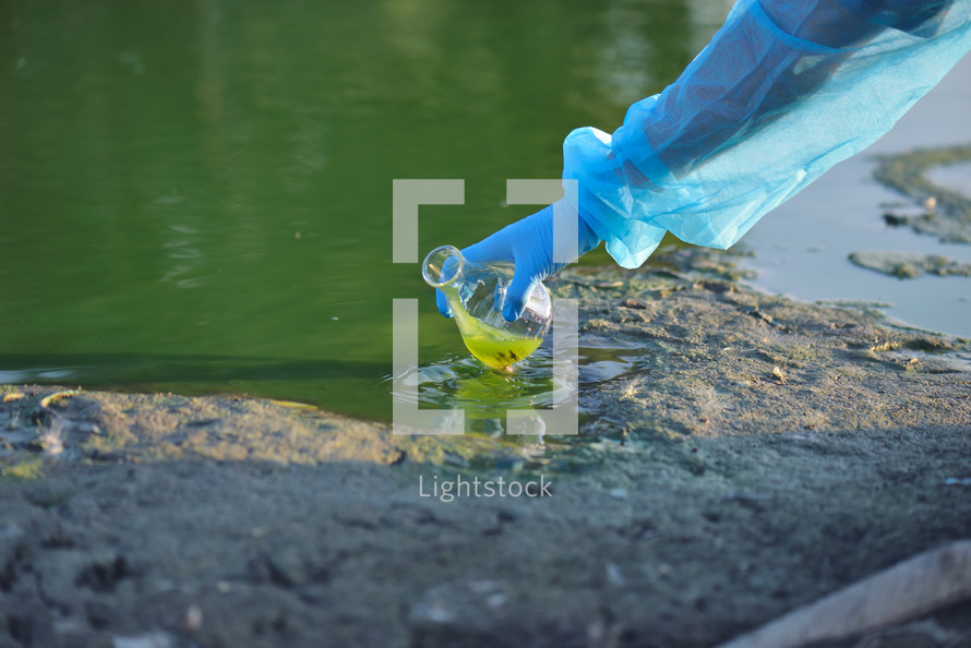 environmentalist hand of a researcher in a process of taking a sample of contaminated water from a lake